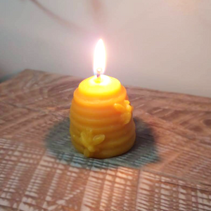 Burning beehive skep candle with two little bees.